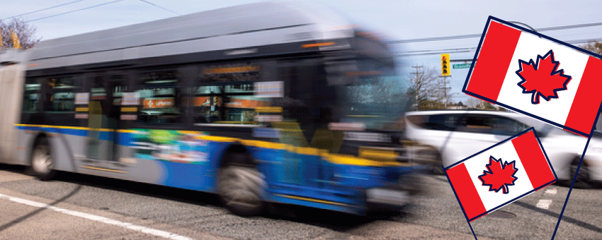 A blurred TransLink bus drives past on a city street, with two illustrated Canadian flags in the foreground, suggesting a Canada Day theme.