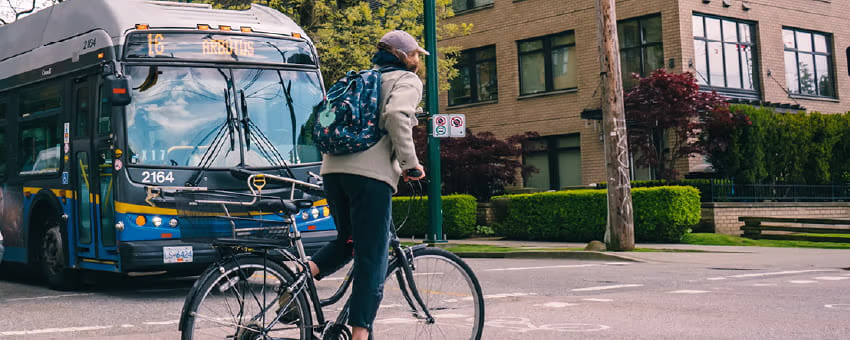 Cyclist riding cross Arbutus street on their bike with the 18 Arbutus bus in the background