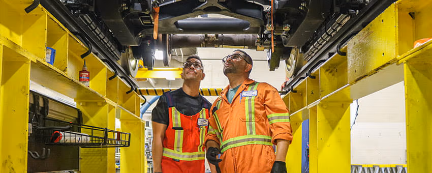 Two TransLink employees looking under a SkyTrain