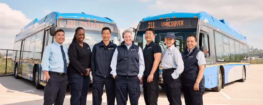 Group of seven bus operators in front of a bus