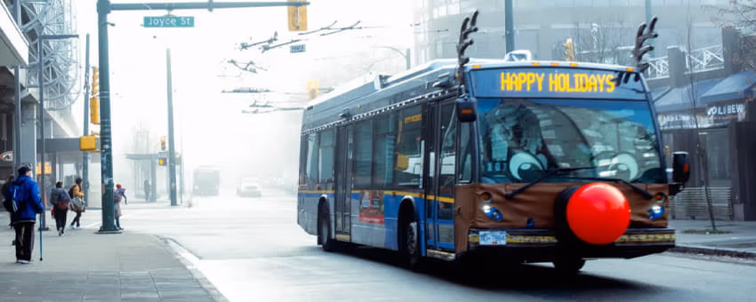 Reindeer Bus driving by Joyce—Collingwood Station and showing Happy Holidays on the destination sign
