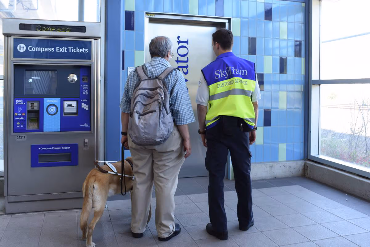 SkyTrain attendant helping a passenger with a guide dog find the elevator
