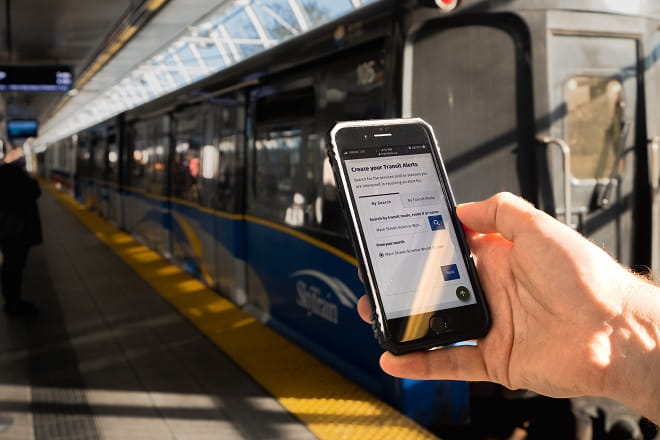 Transit alerts page on phone in front of SkyTrain